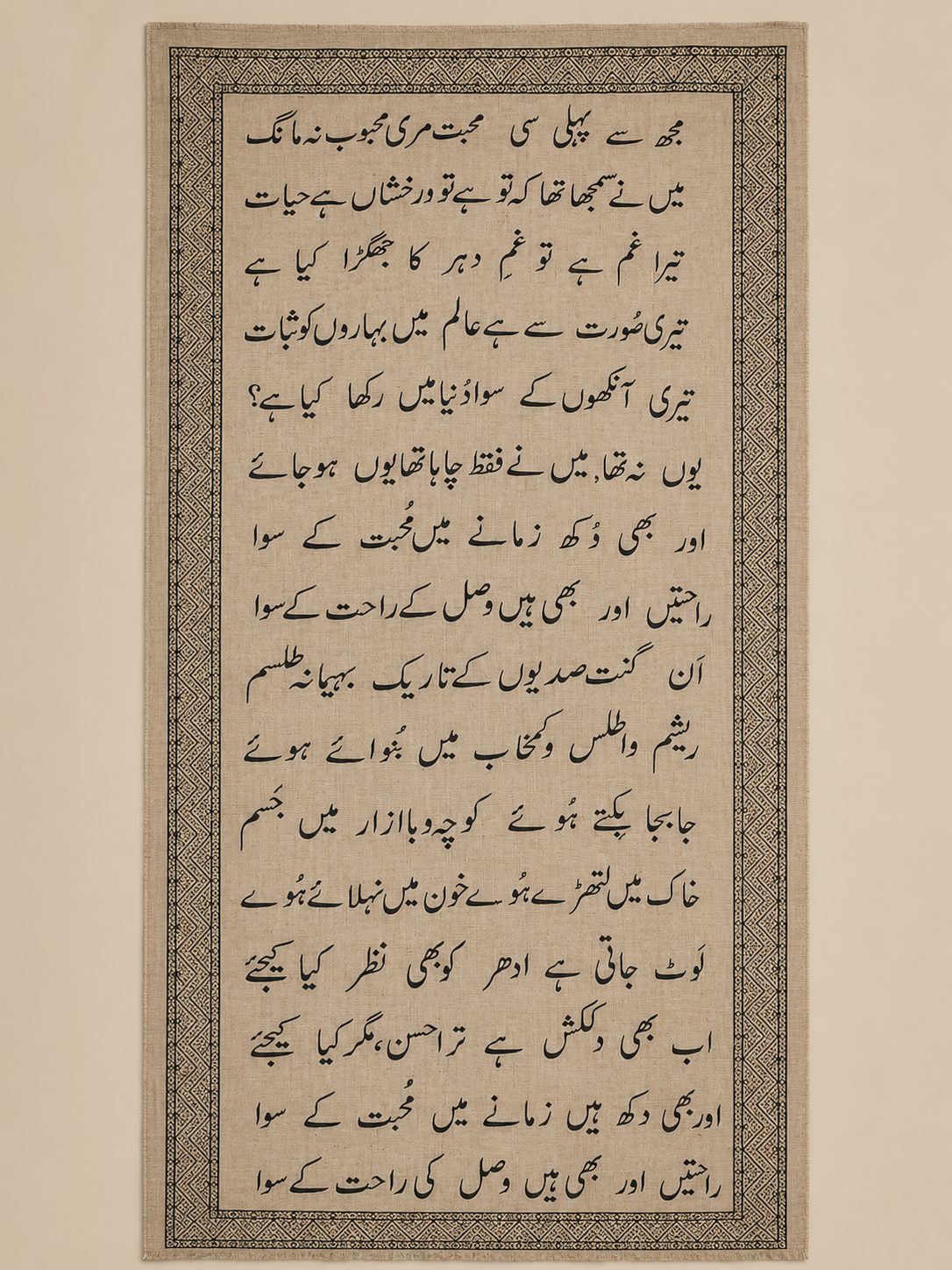 Sandstone pashmina shawl with fine woven geometric border and dark charcoal Urdu script, shown in flat-lay.